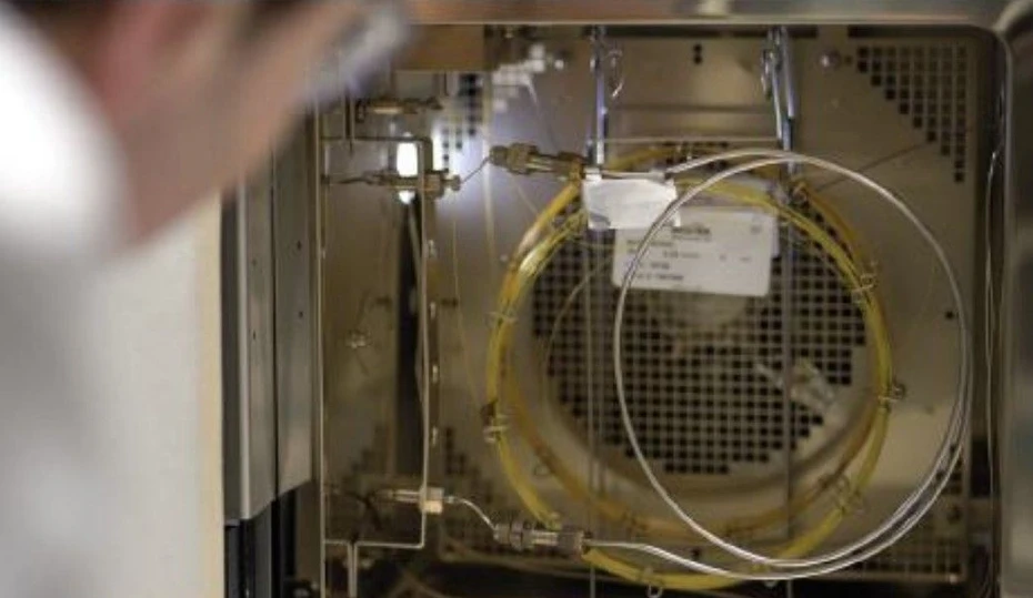 Shimadzu: Obrázek 5: Dr. Michael Sims kontroluje kolonu v peci zakázkového GCMS Shimadzu, v popředí je vidět ochranná kolona a dvě kolony pro separaci sloučenin (žlutá a oranžová). Použití více kolon znamená, že celkový průtok plynu do MS je vyšší než obvykle - to však snadno zvládá vysokokapacitní dvoufázové turbopumpa systému, která je schopna zvládnout až 15 ml/min bez ztráty citlivosti.